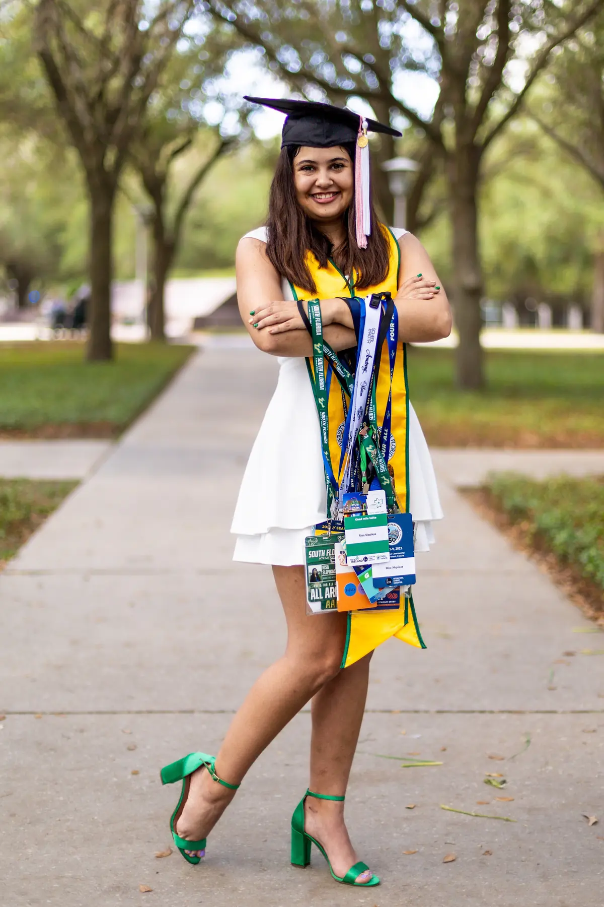 Risa Slepikas in graduation attire with USF academic stole, smiling outdoors on campus
