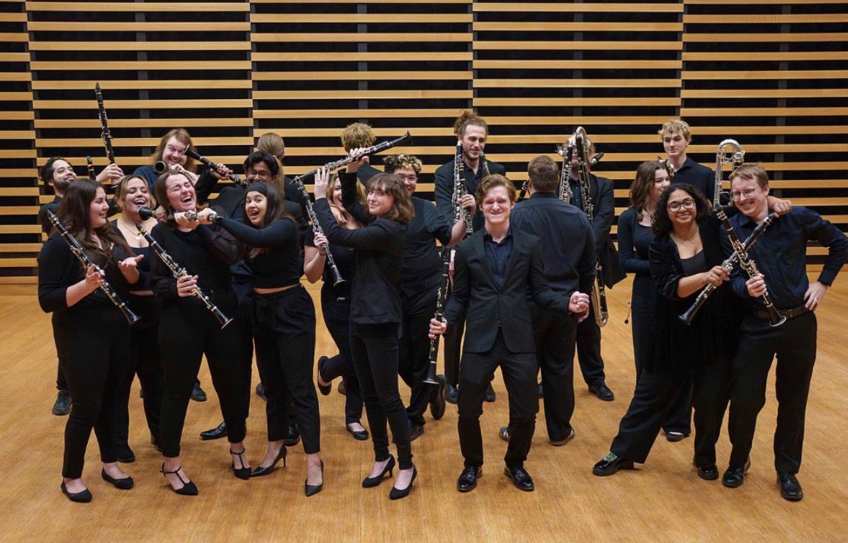USF School of Music clarinet ensemble — young musicians in black concert attire holding clarinets and bass clarinets in a recital hall